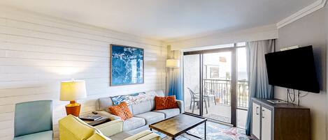Relax in a comfortable seating area with a sofa and armchairs, flat-screen TV, and balcony with outdoor seating.