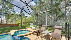 A covered outdoor swimming pool with lounge chairs and a hot tub.