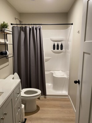 A bathroom with a toilet, shower, and sink.