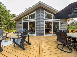 A modern house with a deck, outdoor seating, and a large sliding glass door.