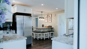 Una cocina moderna con armarios blancos, un refrigerador de acero inoxidable y una isla central con taburetes de bar.