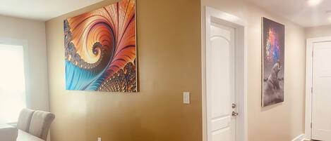 Un pasillo con un comedor, una puerta blanca y dos obras de arte colgadas en la pared.