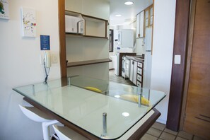 A modern kitchen with a glass-top table, white cabinets, and a microwave. - Leisure, tourism and work with high-speed internet by the sea (Rio de Janeiro)