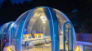 A transparent dome-shaped structure with a bed, seating area, and a small table. - Dream Dome Glamping Studio Ichihara (Ichihara)