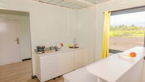 Une cuisine compacte équipée d’une cuisinière, d’un évier et d’une fenêtre donnant sur un espace verdoyant.