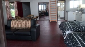 Une pièce compacte comprenant un canapé, un lit, un coin repas et une kitchenette.