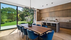Una cocina moderna con armarios de madera, una isla central y un amplio ventanal con vistas a un jardín.