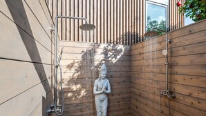 Pared de madera con una estatua, un cabezal de ducha y una manguera.