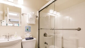 Ein Badezimmer mit einer Duschkabine, einem Waschbecken mit Spiegel und einer Toilette.