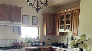 A kitchen with wooden cabinets, a gas stove, a built-in oven, a sink, and a dining area with a white chair.