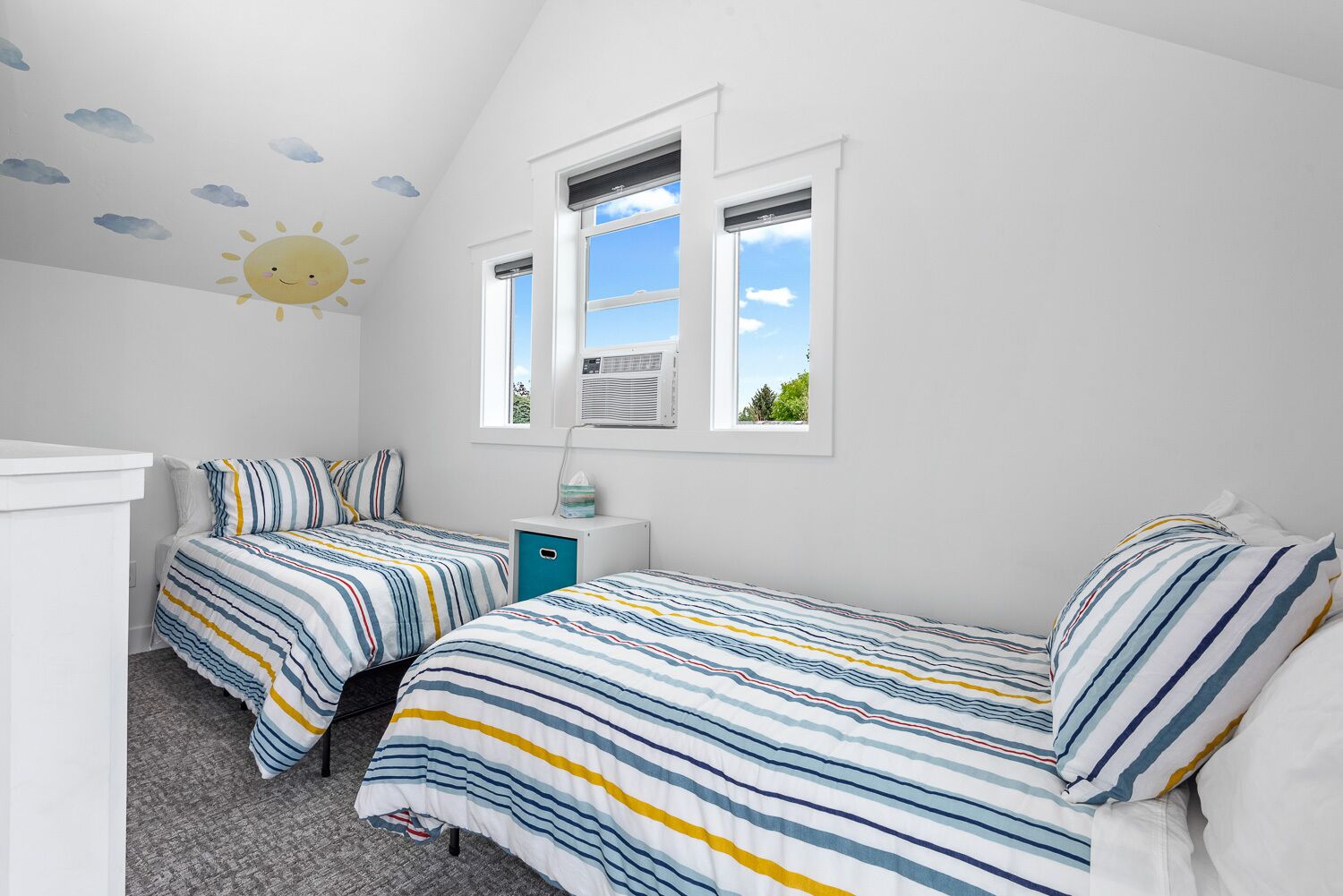 Un dormitorio con dos camas, una ventana y un mural en el techo.