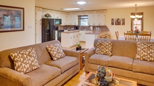 A living room with two sofas, a coffee table, and a dining area with a table and chairs.
