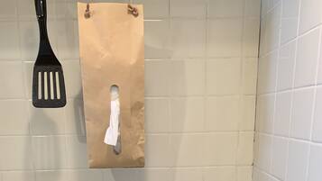 A kitchen with a stove, a hanging paper bag, and a red folder on the counter.