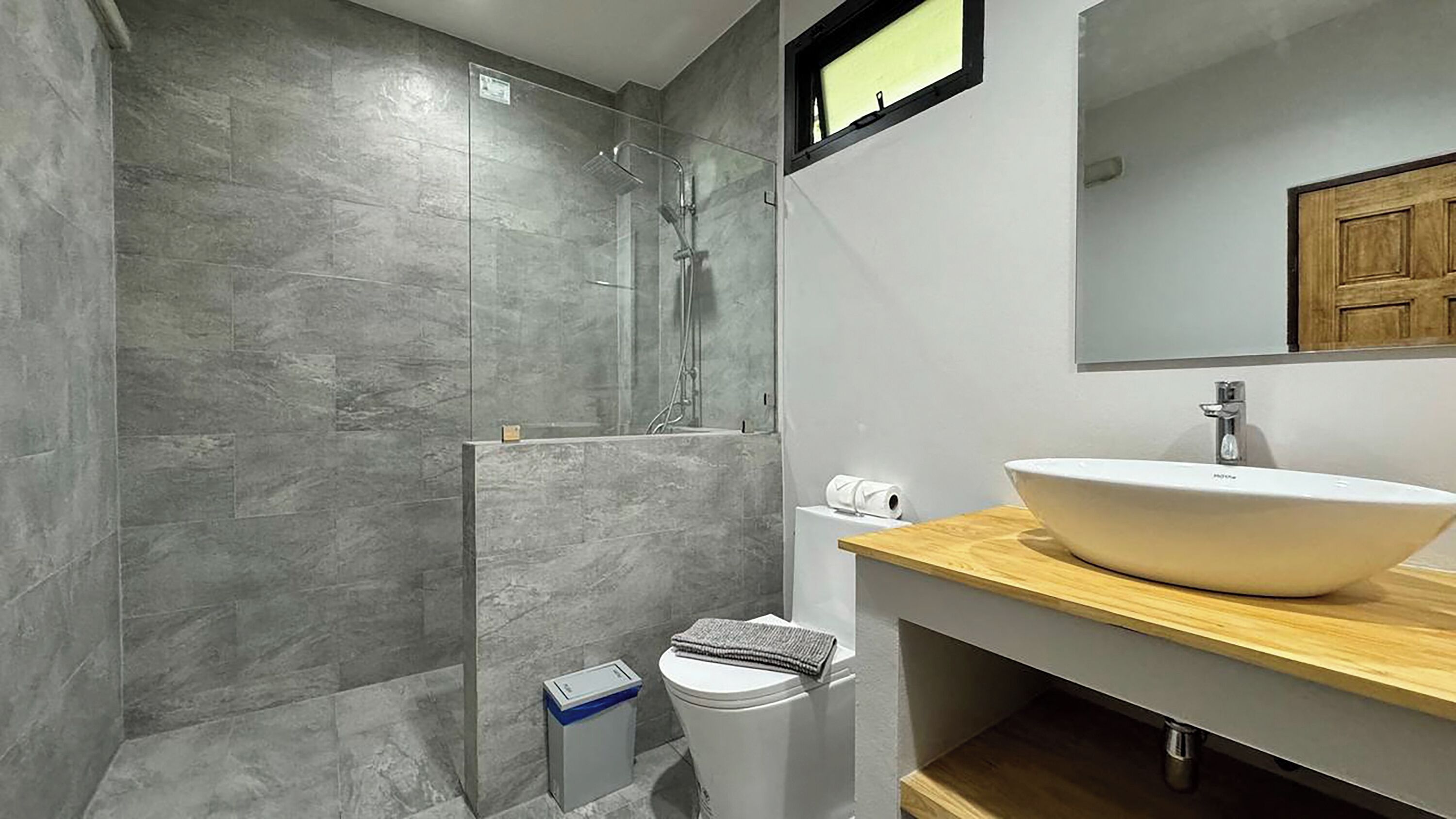 A modern bathroom with a large mirror, a white sink, and a shower enclosure.