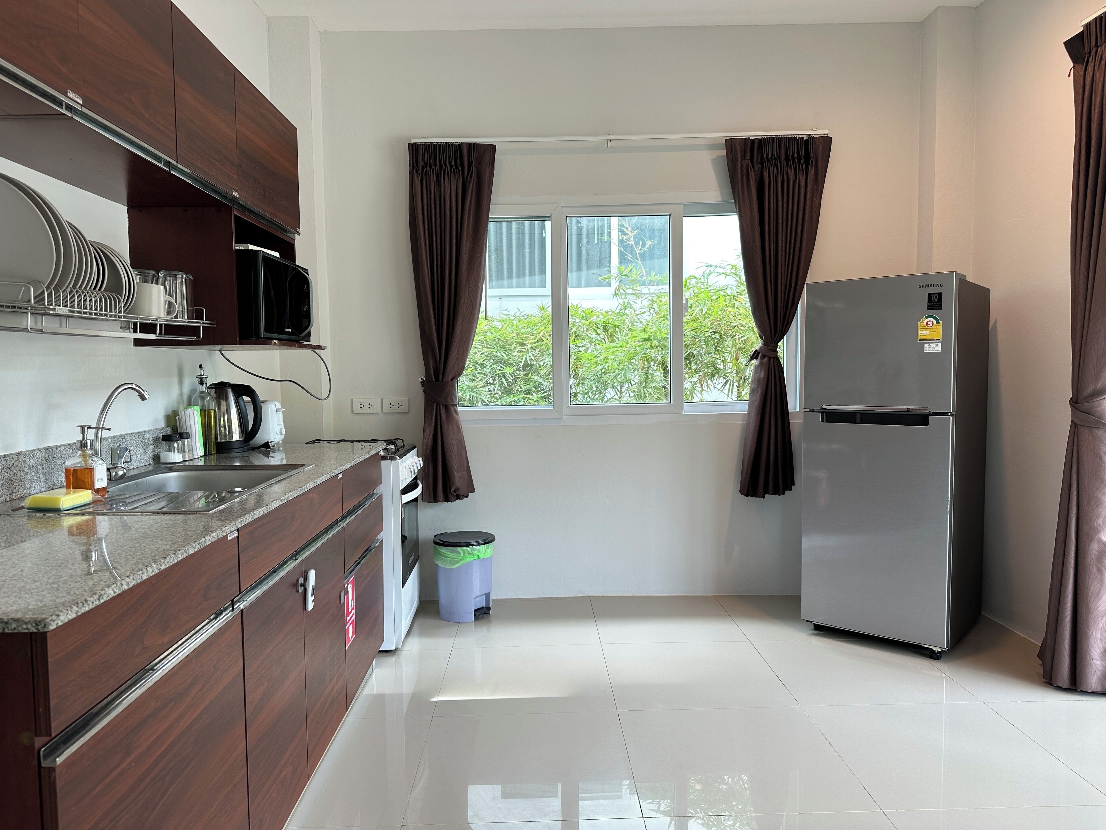 Una cocina moderna con un refrigerador de acero inoxidable, un microondas y un fregadero con escurridor.