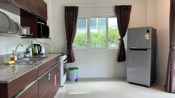 Una cocina moderna con un refrigerador de acero inoxidable, un microondas y un fregadero con escurridor.