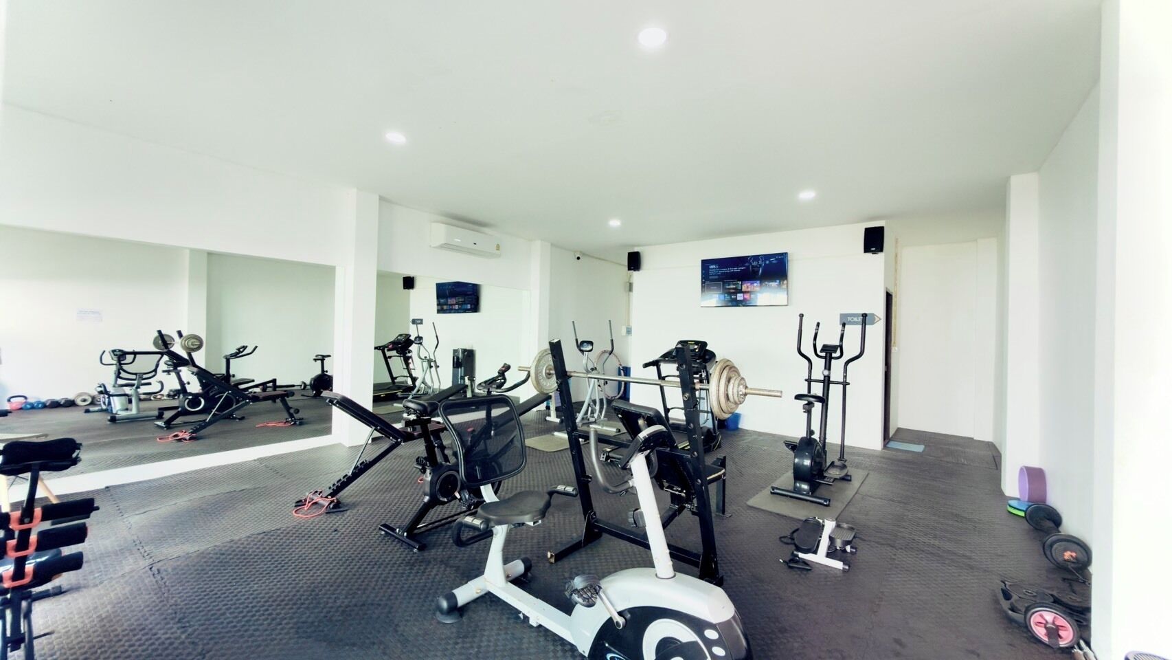 A gym with various exercise equipment, including treadmills, weight machines, and free weights.