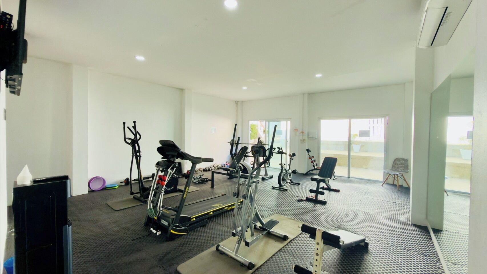 Ein Fitnessstudio mit verschiedenen Trainingsgeräten, darunter Laufbänder, Fahrradergometer und Kraftgeräte.