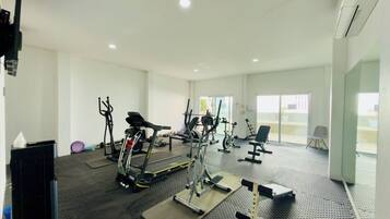 Ein Fitnessstudio mit verschiedenen Trainingsgeräten, darunter Laufbänder, Fahrradergometer und Kraftgeräte.
