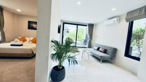 A modern hotel room with a bed, a sofa, a small table, and a potted plant. - Naiwok Hills (Ko Pha-ngan)