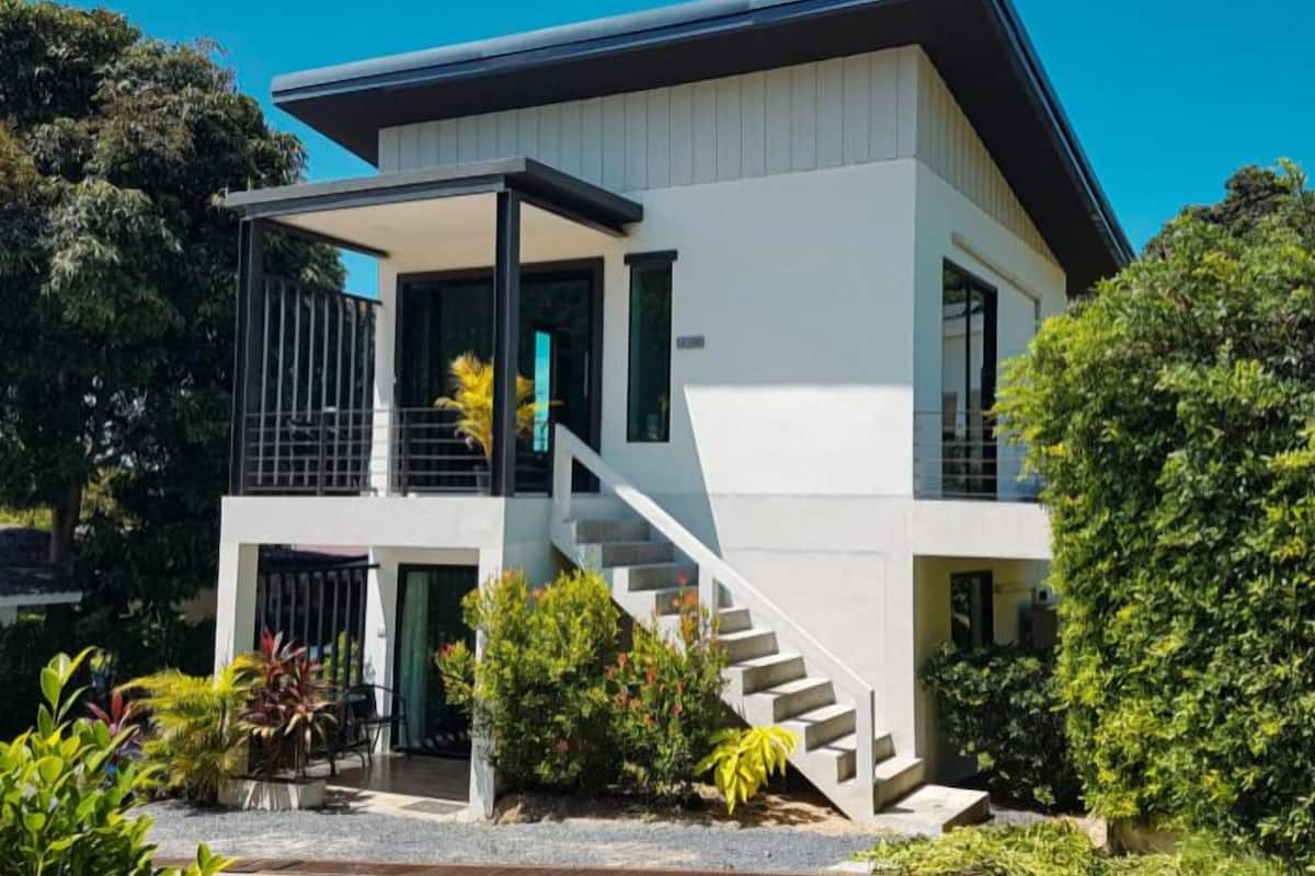Ein modernes, zweistöckiges Haus mit Balkon, Treppe und gepflegtem Garten.