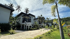 A modern two-story house with a balcony, surrounded by lush greenery and palm trees. - Naiwok Hills (Ko Pha-ngan)