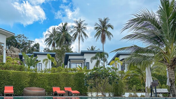 A clear swimming pool with reflections of palm trees and a modern building in the background. - Naiwok Hills (Ko Pha-ngan)