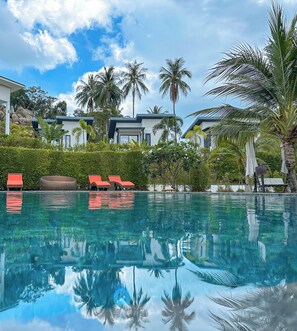 A clear swimming pool with reflections of palm trees and a modern building in the background. - Naiwok Hills (Ko Pha-ngan)