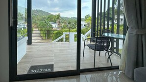 A balcony with a glass door, a metal railing, and a table with two chairs. - Naiwok Hills (Ko Pha-ngan)