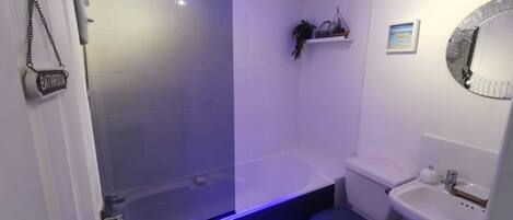 Een badkamer met een douchecabine, een toilet en een wastafel.