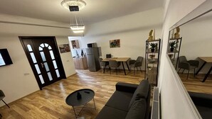 A modern living room with a sofa, a small table, and a dining area with chairs and a table. - Opera Apartment Sleeps 4 with Patio (T'bilisi)