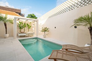 A private pool area with a lounge chair, a swing chair, and potted plants. - Villa Affinity Canggu by OriVista Great Location (Canggu)