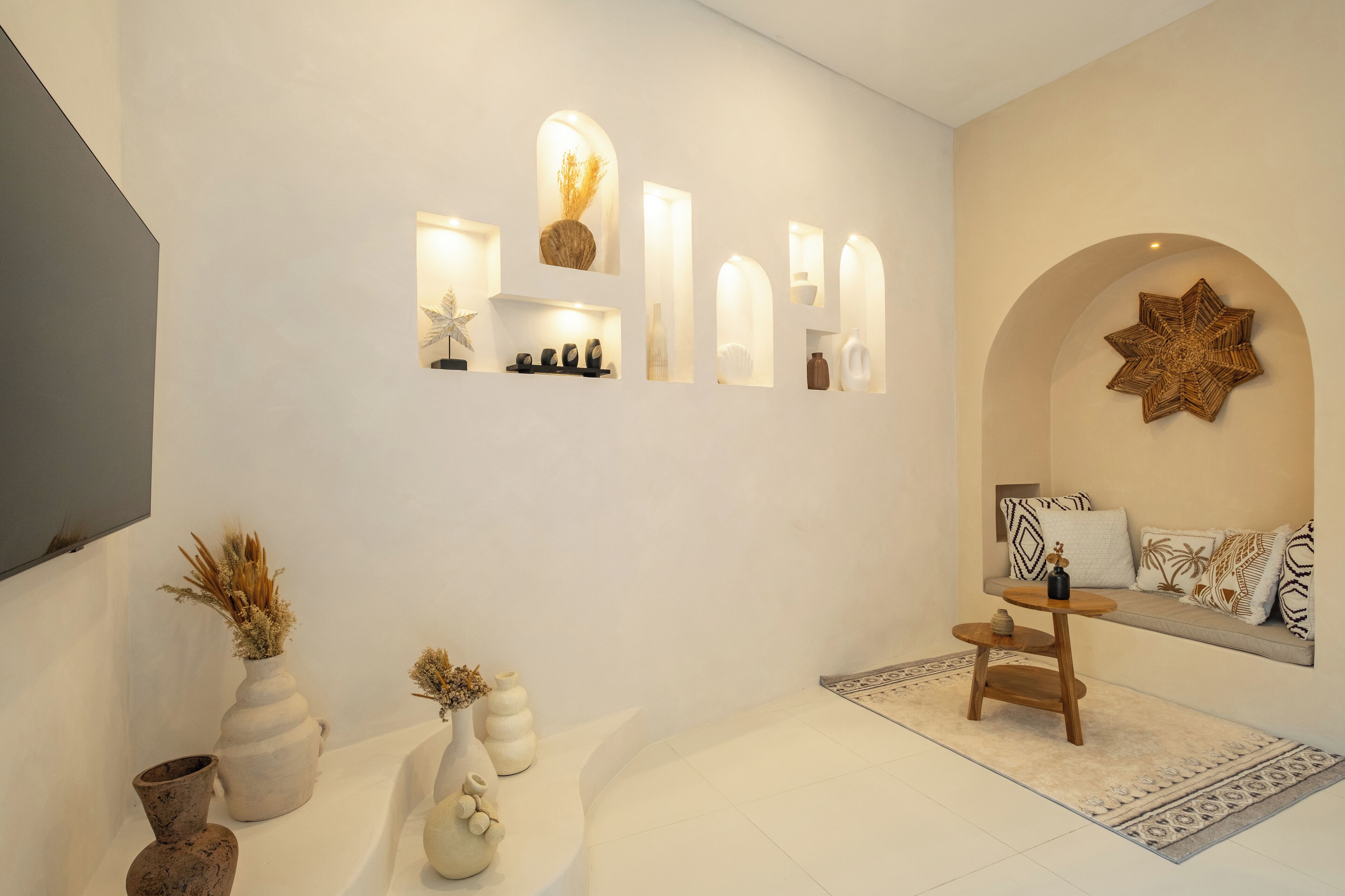 Una sala de estar moderna con un sofá, jarrones decorativos y estantes con iluminación.