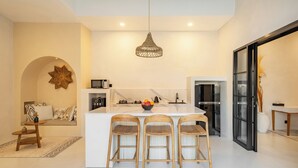 A modern kitchen with a central island, bar stools, a hanging light fixture, and a decorative star on the wall.
