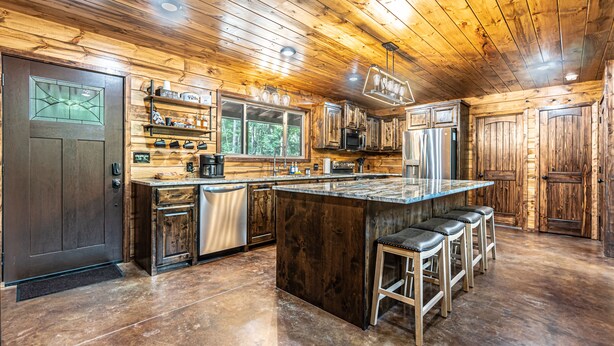 Una cocina amplia con armarios de madera, una isla grande con taburetes de bar y vistas al exterior por la ventana.