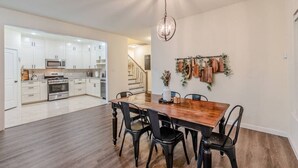 Una cocina moderna con armarios blancos, electrodomésticos de acero inoxidable y una mesa de comedor de madera con sillas negras.