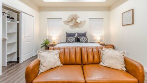 Un dormitorio con una cama grande, un sofá de cuero y un vestidor.