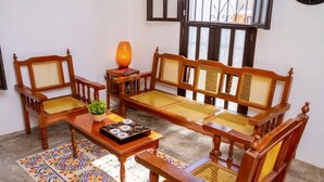 Ein traditionelles Holzsofa-Set mit gewobenen Rückenlehnen und Armlehnen, ein kleiner Tisch mit einer dekorativen Vase und ein gemustertes Teppich.