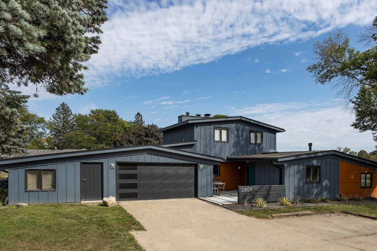 Ein modernes, zweistöckiges Haus mit Garage, überdachter Terrasse und gepflegtem Rasen.