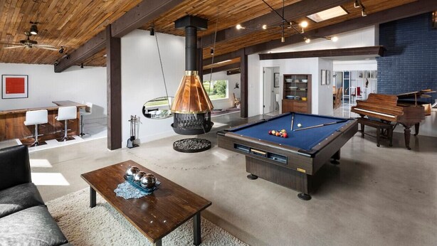 A spacious living area with a pool table, a fireplace, and a dining area with a bench and table.
