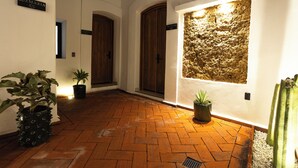 Un pasillo con puertas de madera, suelo de ladrillo y plantas en macetas.