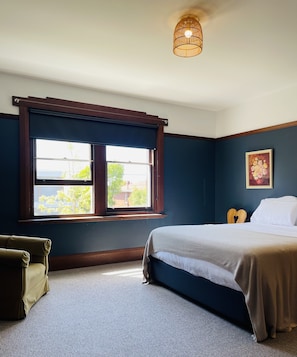 Relax in a cozy space with a neatly made bed, a single chair, and a large window.