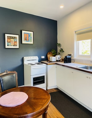 Compact kitchen with a stove, sink, and appliances, adjacent to a dining area with a table and chair.