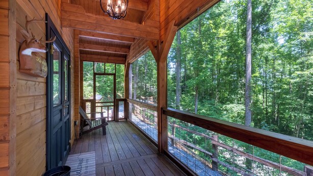 Una cabaña de madera con porche, ventanas amplias y vista a un bosque.