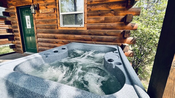 Een houten chalet met een jacuzzi en een groene deur met de tekst 'Yellow'.