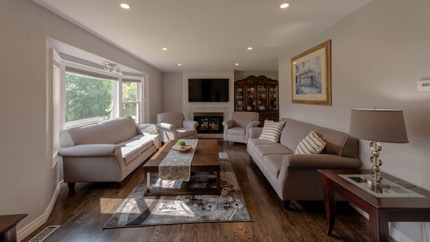 A spacious living room with a fireplace, two sofas, a coffee table, and a TV mounted on the wall. - Entire House with pool in Niagara-on-the-lake close to Niagara Falls (Niagara-on-the-Lake)