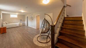 A spacious room with a wooden staircase, a hanging chair, and a bed. - Entire House with pool in Niagara-on-the-lake close to Niagara Falls (Niagara-on-the-Lake)
