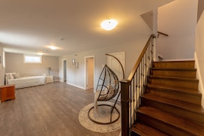 Une pièce spacieuse avec un escalier en bois, un fauteuil suspendu et un lit.