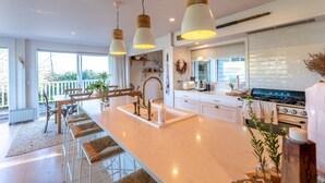 A modern kitchen with a central island, stainless steel appliances, and pendant lighting. - Oriwa Villa Oneroa near Mudbrick (Waiheke Island)