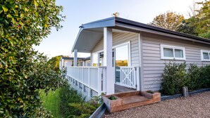 A single-story house with a covered porch, white railings, and a gravel driveway. - Oriwa Villa Oneroa near Mudbrick (Waiheke Island)